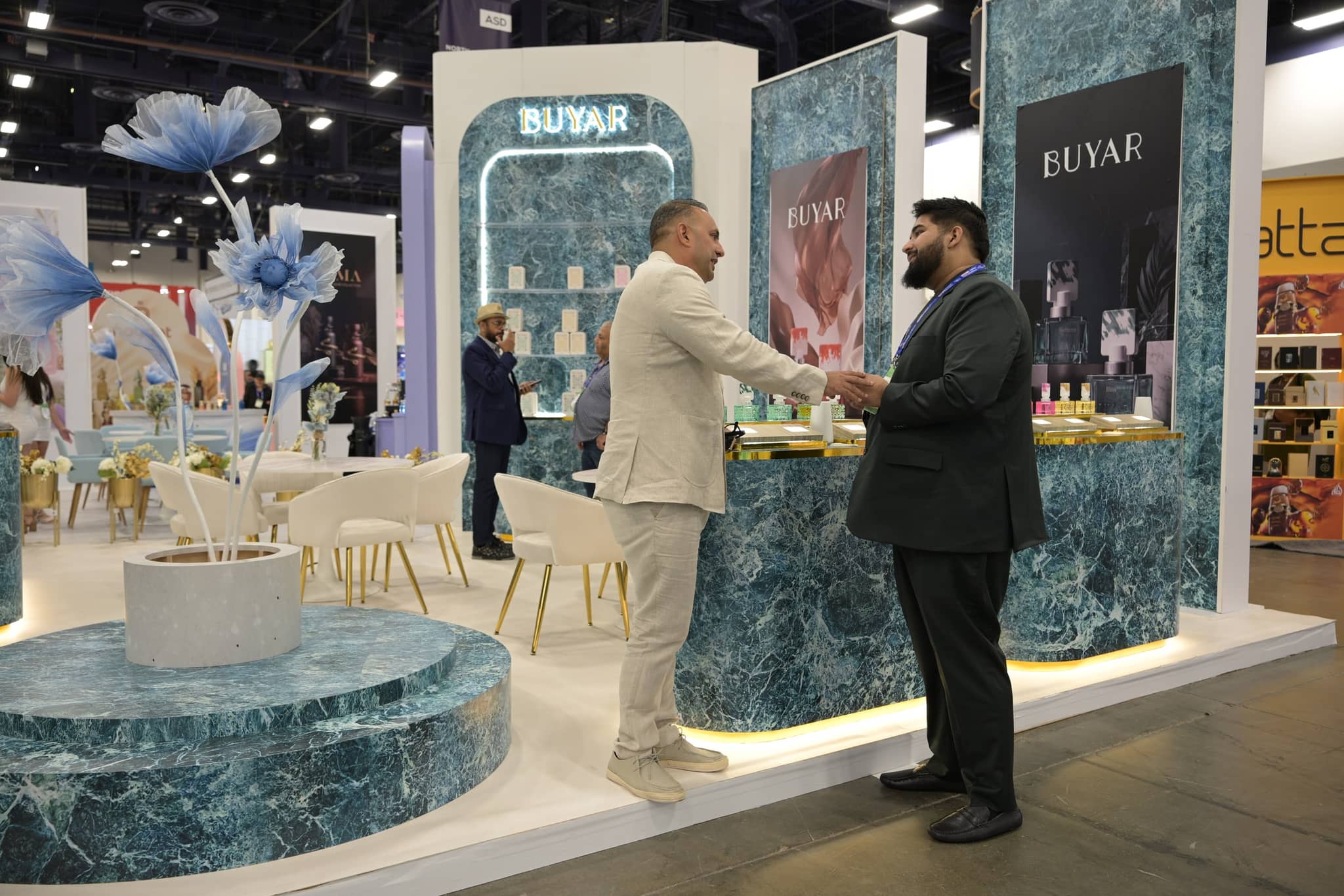 Two attendees shaking hands at the BUYAR fragrance booth