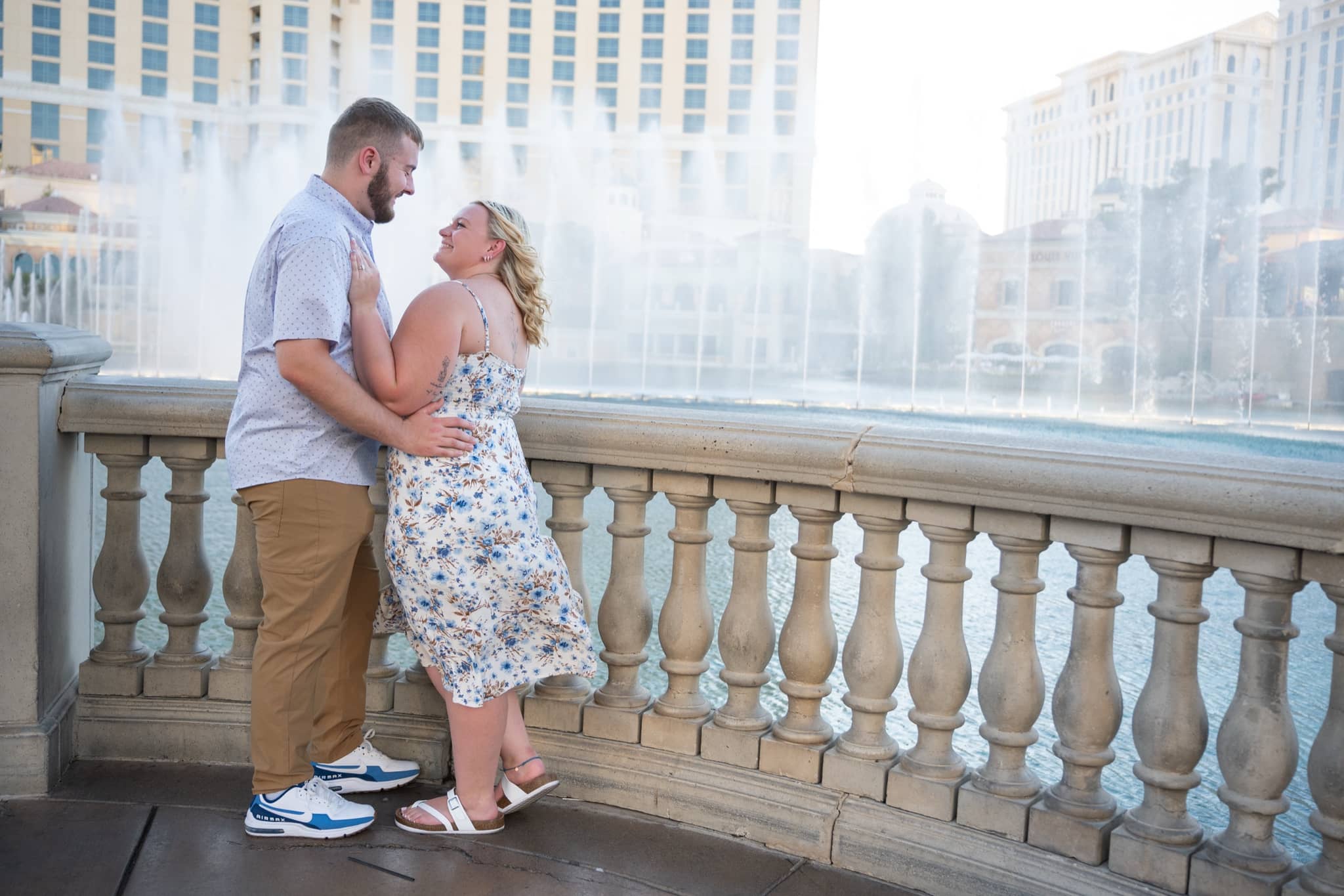 Couple smiling at each other in front of the fountains on the Las Vegas Strip during their engagement session