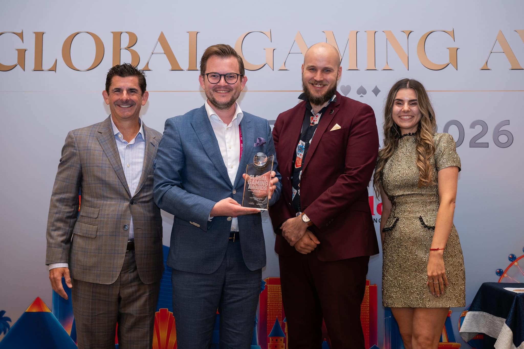 Award winner holding a trophy with presenters at the Global Gaming Awards Americas 2026
