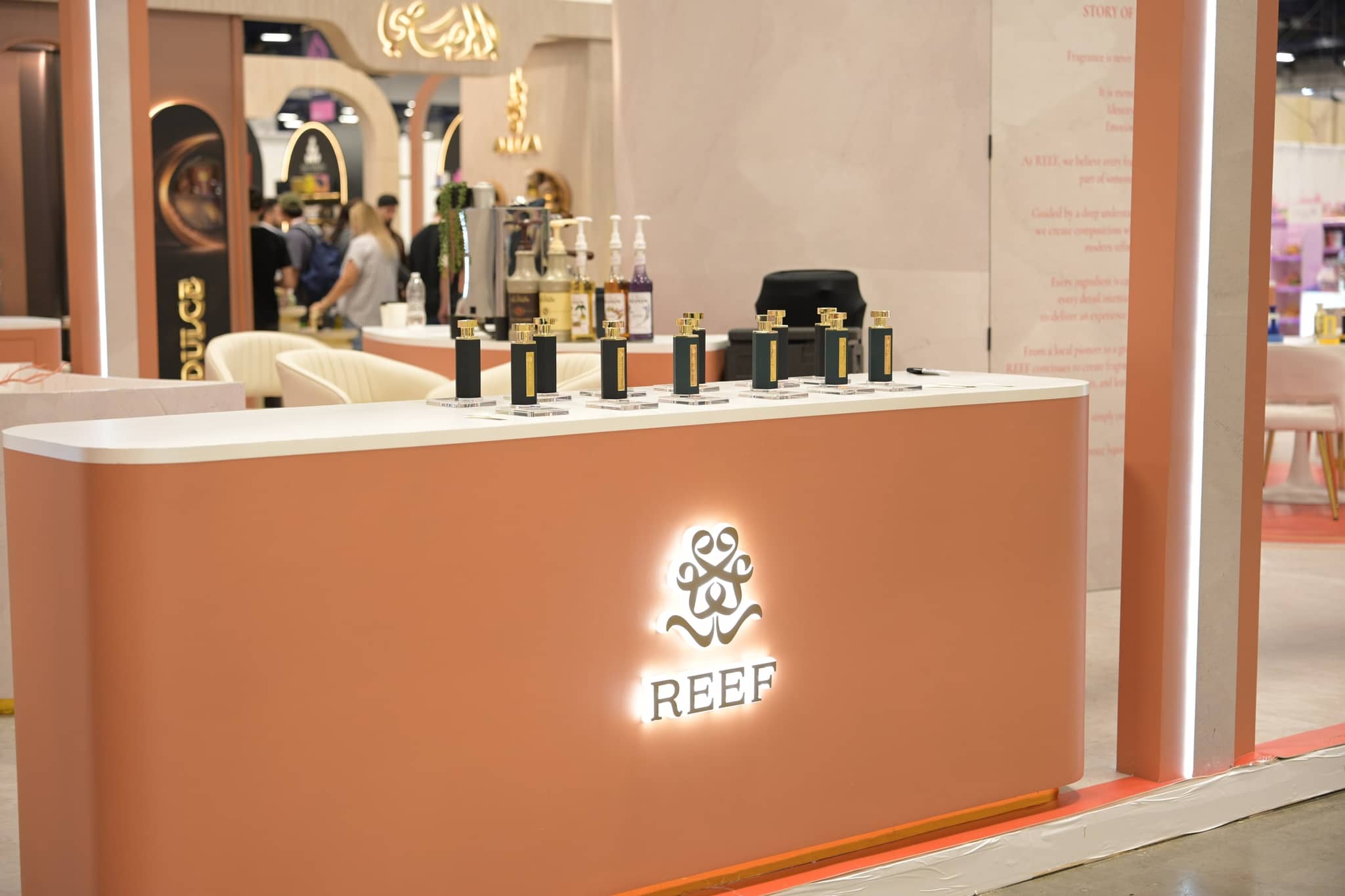 Illuminated REEF booth counter displaying fragrance bottles